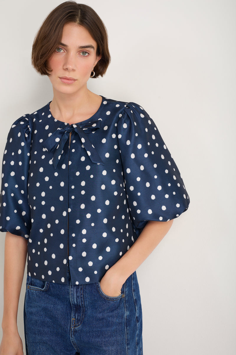 Model wearing a navy spot print top with balloon sleeves