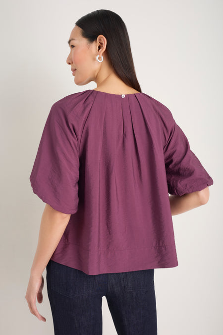 Back view of model in a plum-colored blouse