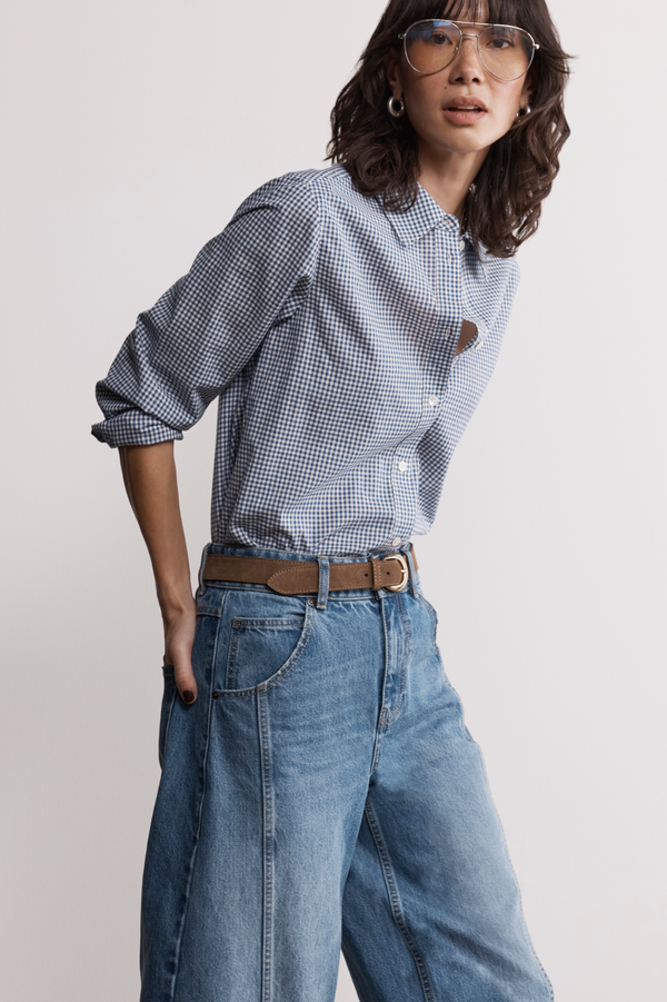 Model with a jumper draped over shoulders wearing a midnight blue gingham shirt