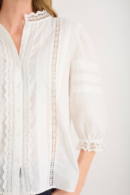 Detailed close-up of lace trim and pintucks on an ivory blouse