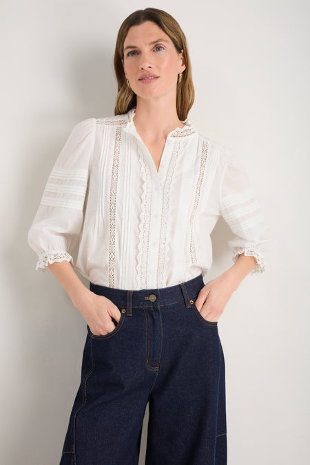 Model wearing an ivory cotton blouse with pintuck details and 3/4 sleeves