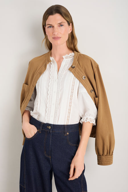 Model in ivory blouse wearing a tan open cardigan