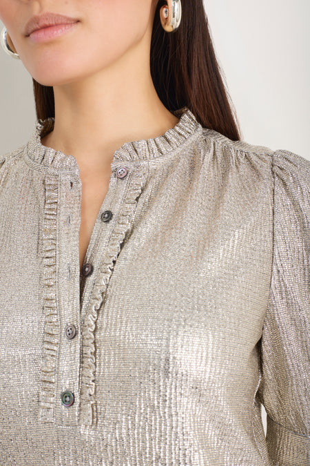 Close-up of the frilled collar and button placket on a champagne metallic top