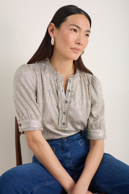 Model wearing a shimmering champagne short-sleeved top with frilled collar