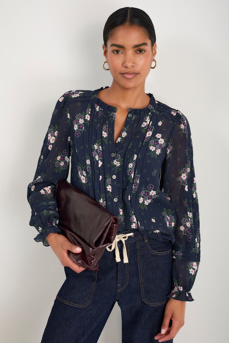 Model wearing a dark blue blouse with a white floral print.