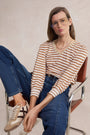 Woman wearing a striped shirt and jeans sitting on a chair.